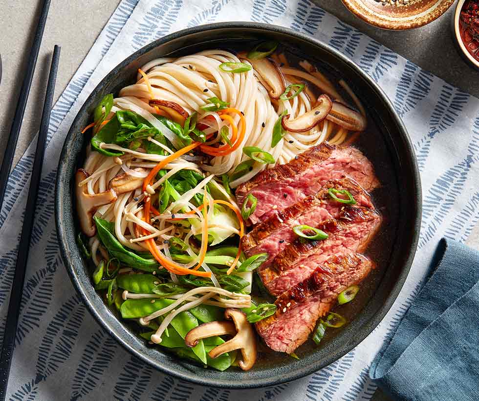 Serving of beef ramen that includes noodles, vegetables and sliced beef