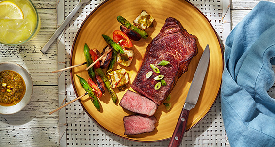 Beef strip loin plated with colorful vegetable kebabs