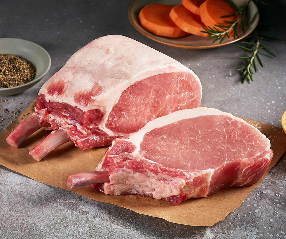 Three raw bone-in pork chops laying on butcher paper