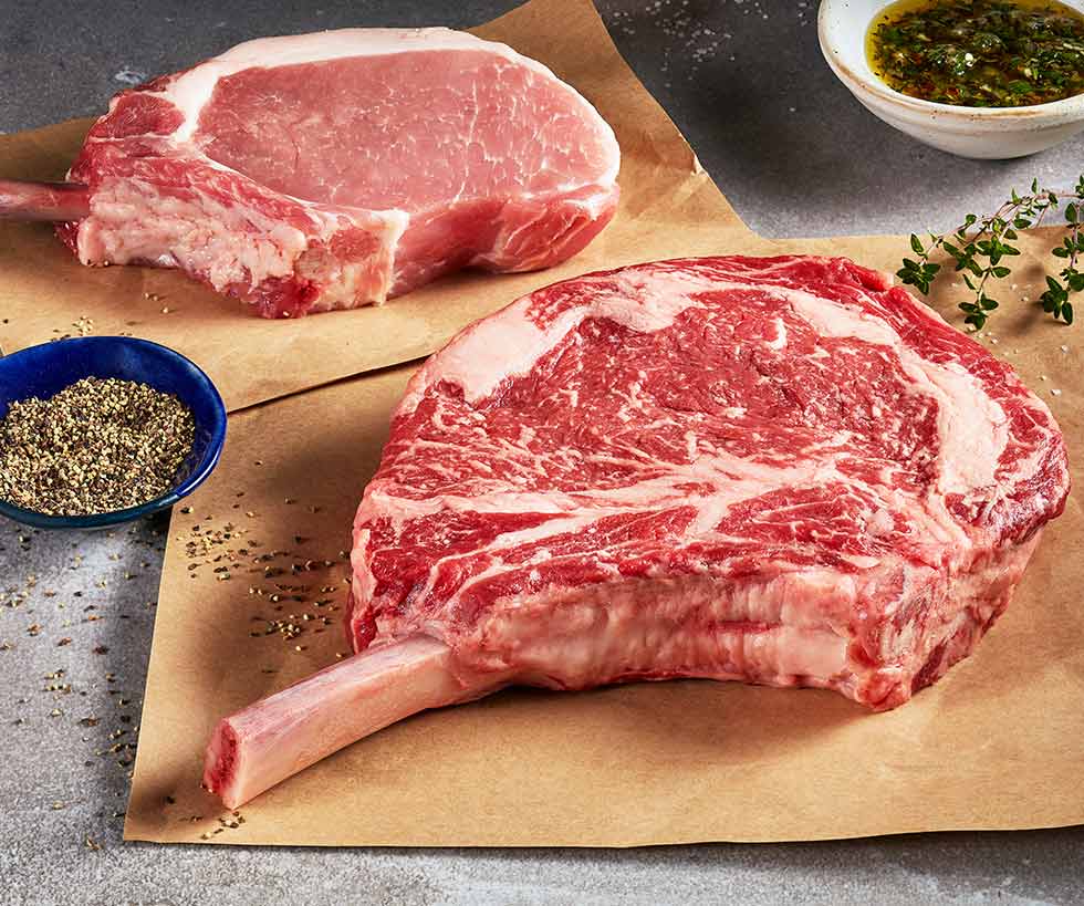 Raw ribeye steak and raw pork chop laying on butcher paper
